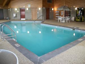 a large swimming pool in a building with a table and chairs at AmericInn by Wyndham Beulah in Beulah