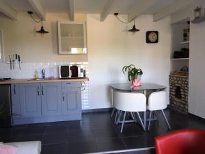 a kitchen with blue cabinets and a table and chairs at Le Gîte de Montine proche Puy du Fou in Chantonnay +17 photos