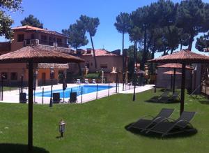 una piscina con sillas y sombrillas en un patio en La Villa Don Quijote, en Cuenca