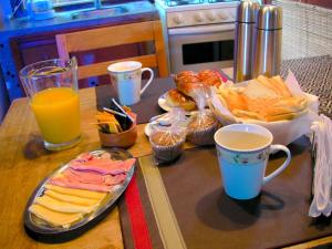 una mesa con una bandeja de comida y tazas de zumo de naranja en Altos Medanos Cabañas & Club de Bosque en Mar de las Pampas