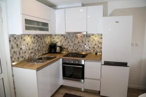 una cocina con armarios blancos y fregadero en Apartments Sunset en Hvar