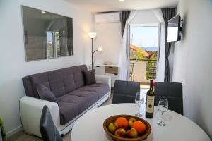 Apartments Sunset في هفار: غرفة معيشة مع أريكة وطاولة مع وعاء من الفاكهة