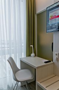 a desk with a television and a chair in front of a window at Super 8 by Wyndham Munich City West in Munich
