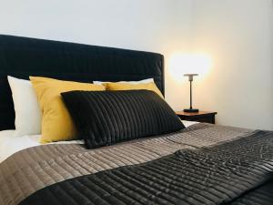 a bed with a black comforter and yellow pillows at AMBER Guest Rooms in Krakow