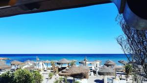 una spiaggia con molti ombrelloni di paglia e l'oceano di Corallo casa vacanza a Villaputzu