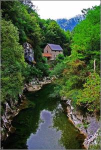 Un río con una casa al lado de una montaña en Las Cabraliegas, en Arenas de Cabrales