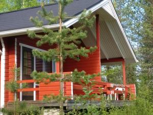 a red cabin with a tree in front of it at Rieskapaikka in Koivu