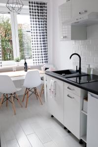 eine weiße Küche mit einem Waschbecken und weißen Stühlen in der Unterkunft Kamienica Wygon Apartment in Danzig