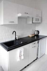 eine weiße Küche mit einer schwarzen Arbeitsplatte in der Unterkunft Kamienica Wygon Apartment in Danzig