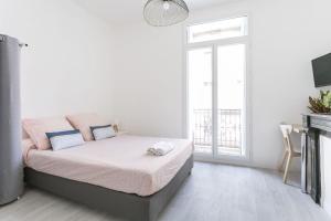 a white bedroom with a bed and a window at Sunny Relaxing Apartement in Béziers