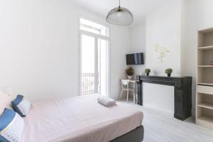 a white bedroom with a bed and a tv at Sunny Relaxing Apartement in Béziers
