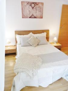 um quarto com uma cama branca com duas mesas de cabeceira em tarragonaapartments arrabassada beach em Tarragona