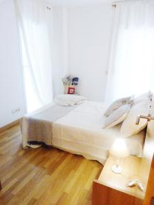 um quarto com uma cama e uma mesa com um candeeiro em tarragonaapartments arrabassada beach em Tarragona