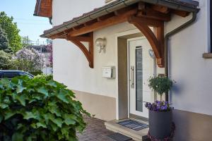 Une porte menant à une maison avec des fleurs. dans l'établissement BodenSEE Apartment Friedrichshafen SEENAH, à Friedrichshafen