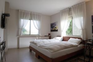 a bedroom with a large bed in front of two windows at Bait Bagiva in Bet ‘Oved