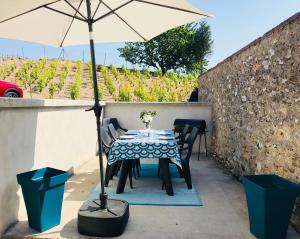 una mesa y sillas con una sombrilla en el patio en Le Clos de Clara, en Pierry