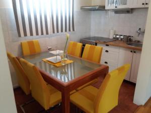 a kitchen with a glass table and yellow chairs at Crystal Kragujevac in Kragujevac