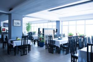 a dining room with white tables and chairs and windows at Cormoran Resort in Uzlina