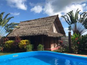 a cottage with a swimming pool in front of it at L'ESCALE in Nosy Be