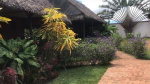 a garden with flowers and a house with a brick path at L'ESCALE in Nosy Be