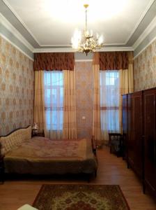 Schlafzimmer mit einem Bett und Vorhängen sowie einem Kronleuchter in der Unterkunft Guesthouse Panorama in Kutaissi