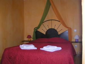 Un dormitorio con una cama roja con toallas. en Hotel Des Sites, en Salavas