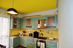 een keuken met groene kasten en een geel plafond bij Apartments Kaloj in Tirana