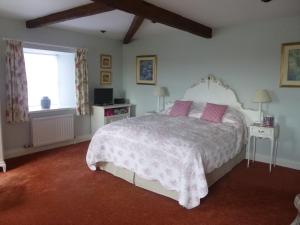 a bedroom with a white bed with pink pillows and a window at The Gin Gan in Hexham