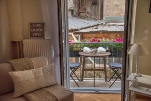 Zimmer mit einem Balkon mit einem Tisch und einem Fenster in der Unterkunft Living near Acropolis by Sylvia Staikou in Athen