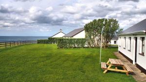 um quintal com um banco de madeira ao lado de uma casa em Quilty Holiday Cottages - Type A em Quilty