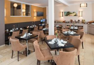 a restaurant with tables and chairs and a counter at Hotel New Orly in Munich