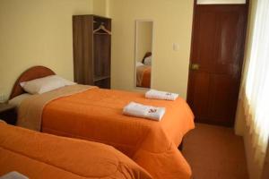 a bedroom with two beds with orange sheets and a mirror at Peru Swiss Hostel in Arequipa