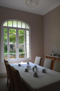 mesa blanca con sillas y ventana grande en La maison d'Antoine Rivesaltes, en Rivesaltes