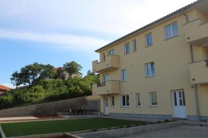 a building with a grass yard in front of it at Apartmani Marin in Vrbnik