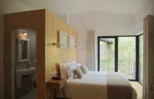 a bedroom with a bed and a sink and a window at Original Douro Hotel in Peso da Régua