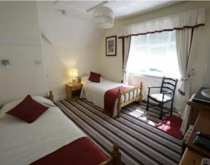 um quarto com 2 camas, uma cadeira e uma janela em Bodhyfryd Guesthouse em Betws-y-coed