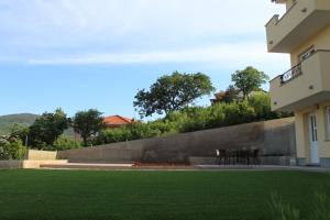 a lawn in front of a building with two chairs at Apartmani Marin in Vrbnik +3 photos