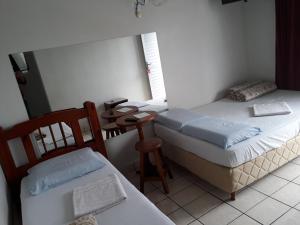 two beds in a room with a table and chairs at Previato Hotel in Curitiba