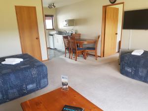 a living room with a table and a kitchen at Mt Cook View Motel in Fox Glacier