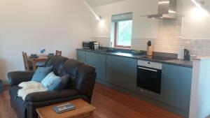 a living room with a couch and a kitchen at Curlew Cottage in Eyre