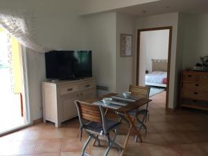 ein Wohnzimmer mit einem Tisch, Stühlen und einem TV in der Unterkunft appartement acqua dolce in Saint-Florent