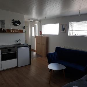 salon z niebieską kanapą i kuchnią w obiekcie Hólavegur 6 w mieście Sauðárkrókur