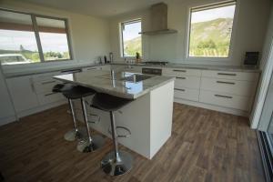 a kitchen with a island with a sink and two windows at Fox Cottage in Ashwick Flat