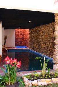 a swimming pool with a stone wall and flowers at Casa Rayma in Contratacion