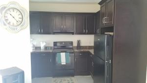 a kitchen with black cabinets and a clock on the wall at villa serena 4 Beds, 2 Bath in Rosarito