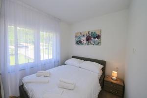 a white bedroom with a bed with two towels on it at Villa Martina in Ika