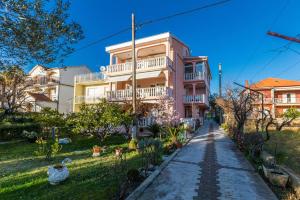 ein rosa Haus mit einem Bürgersteig davor in der Unterkunft Sea View Apartments Pericic in Sukošan