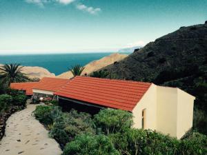 a building with an orange roof on a beach at Casa ALMA in Hermigua