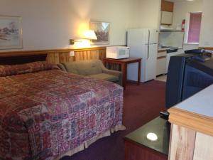 a hotel room with a bed and a refrigerator at Rainbow Motor Inn in Chilliwack