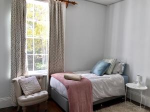 ein Schlafzimmer mit einem Bett, einem Fenster und einem Stuhl in der Unterkunft Robin Hoods Well Farm Stay in Sassafras